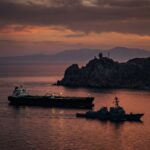 Oil tanker and naval ship at sunset